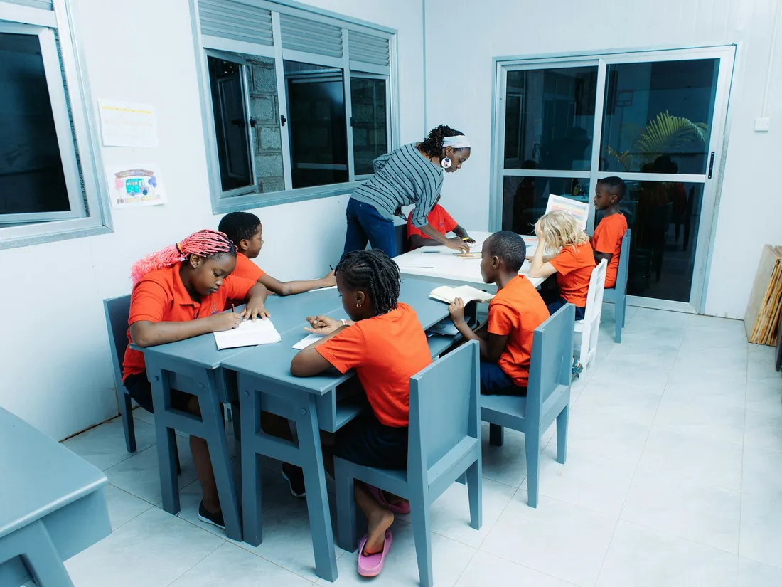 A teacher helping pupils with their work in a bright classroom