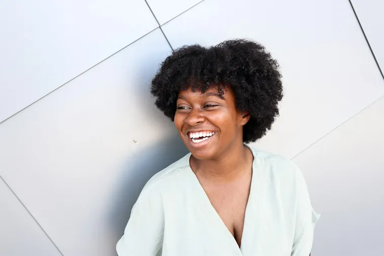 A woman laughing against a white wall