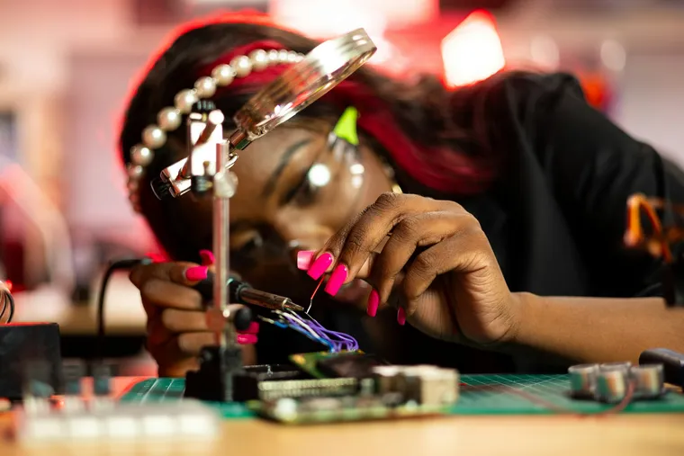 An engineer soldering a circuit board under a magnifier