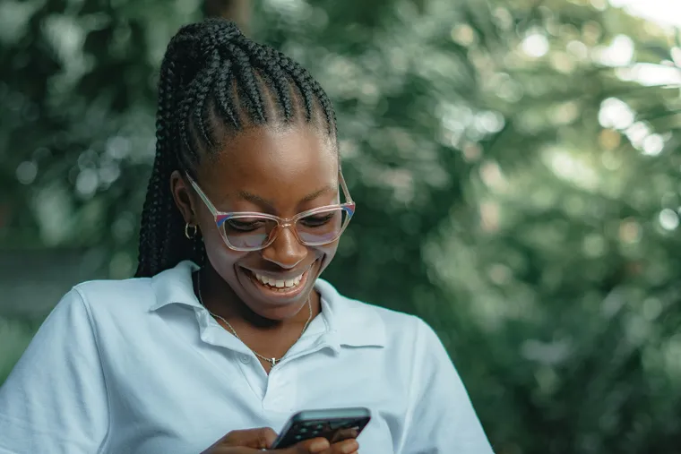 A woman in glasses smiling at her phone