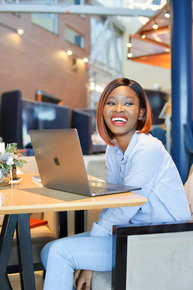 A woman smiling at her laptop in a bright home office