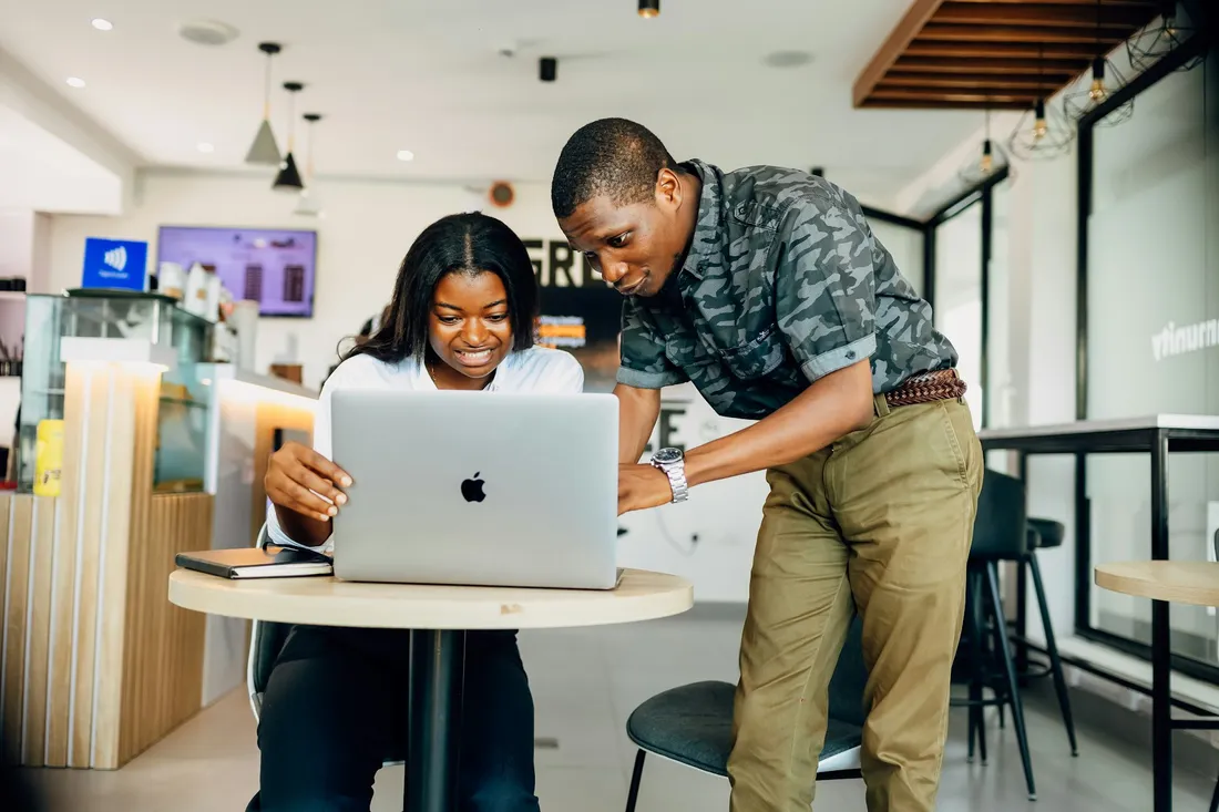 Two colleagues smiling over a laptop in a bright office