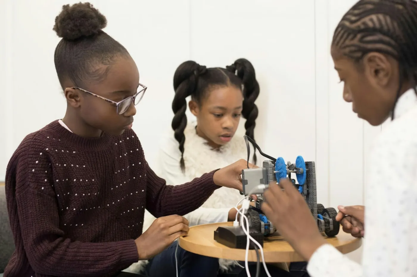 Three girls building and testing a small robot together
