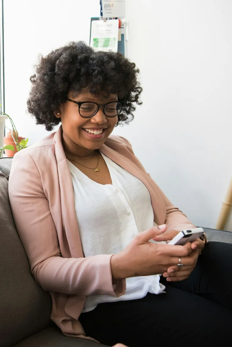 A smiling woman in glasses using her phone